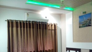 A hotel room with two beds, a desk, and a chair. - Hotel Decent (Surat)