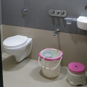 Un baño con inodoro, lavamanos y un cubo de basura.