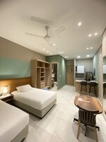 Habitación de hotel con cama, escritorio, silla, armario y baño visible a través de una puerta abierta.