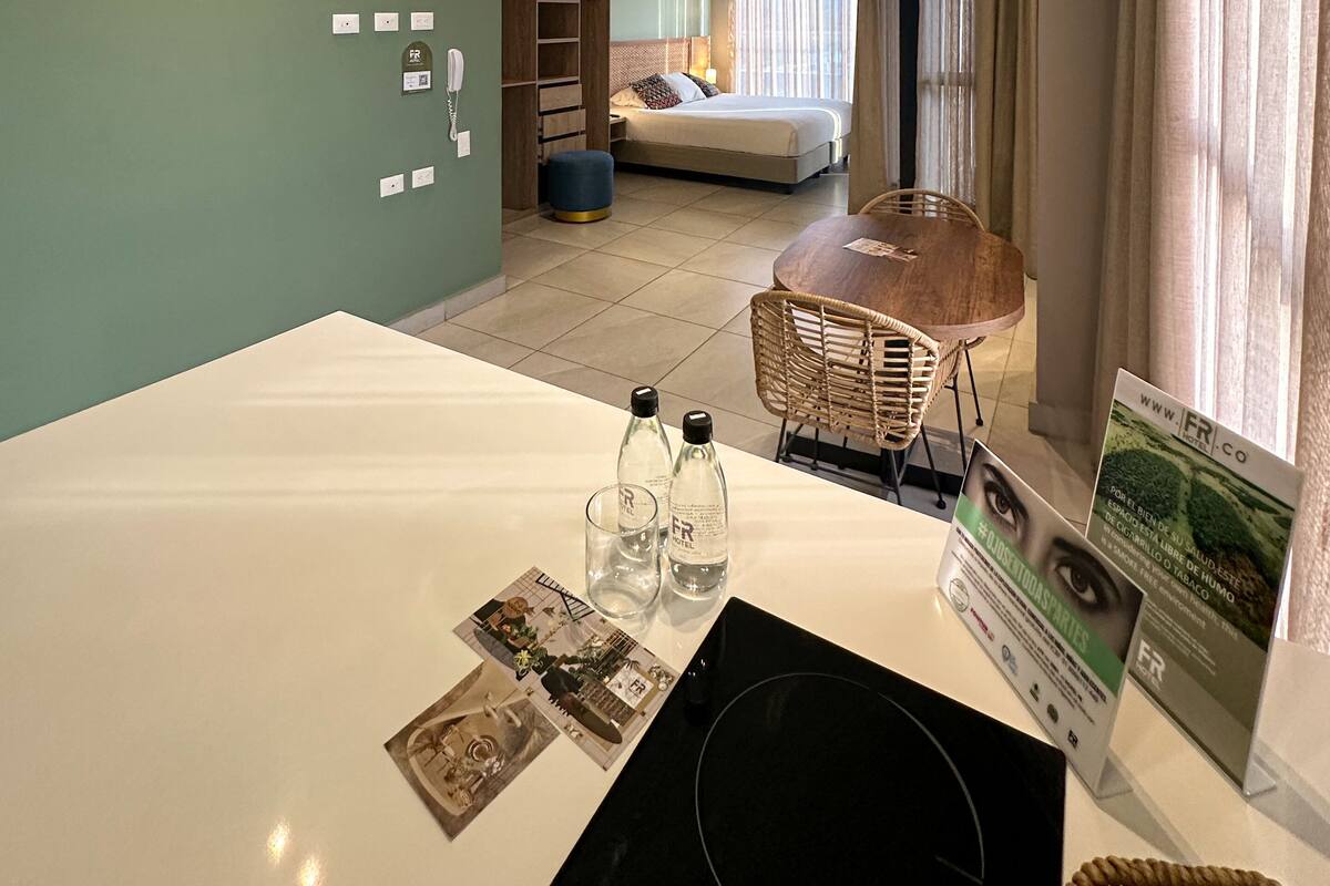 A modern hotel room with a dining area, a bed, and a view of the outdoors.