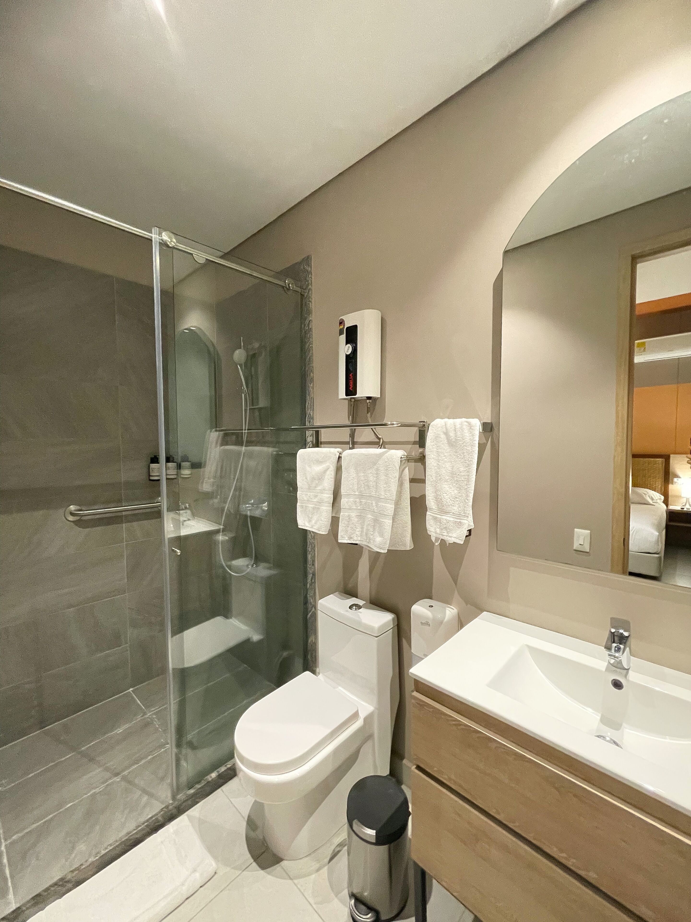 A modern bathroom with a glass-enclosed shower, a toilet, a sink, and a mirror.