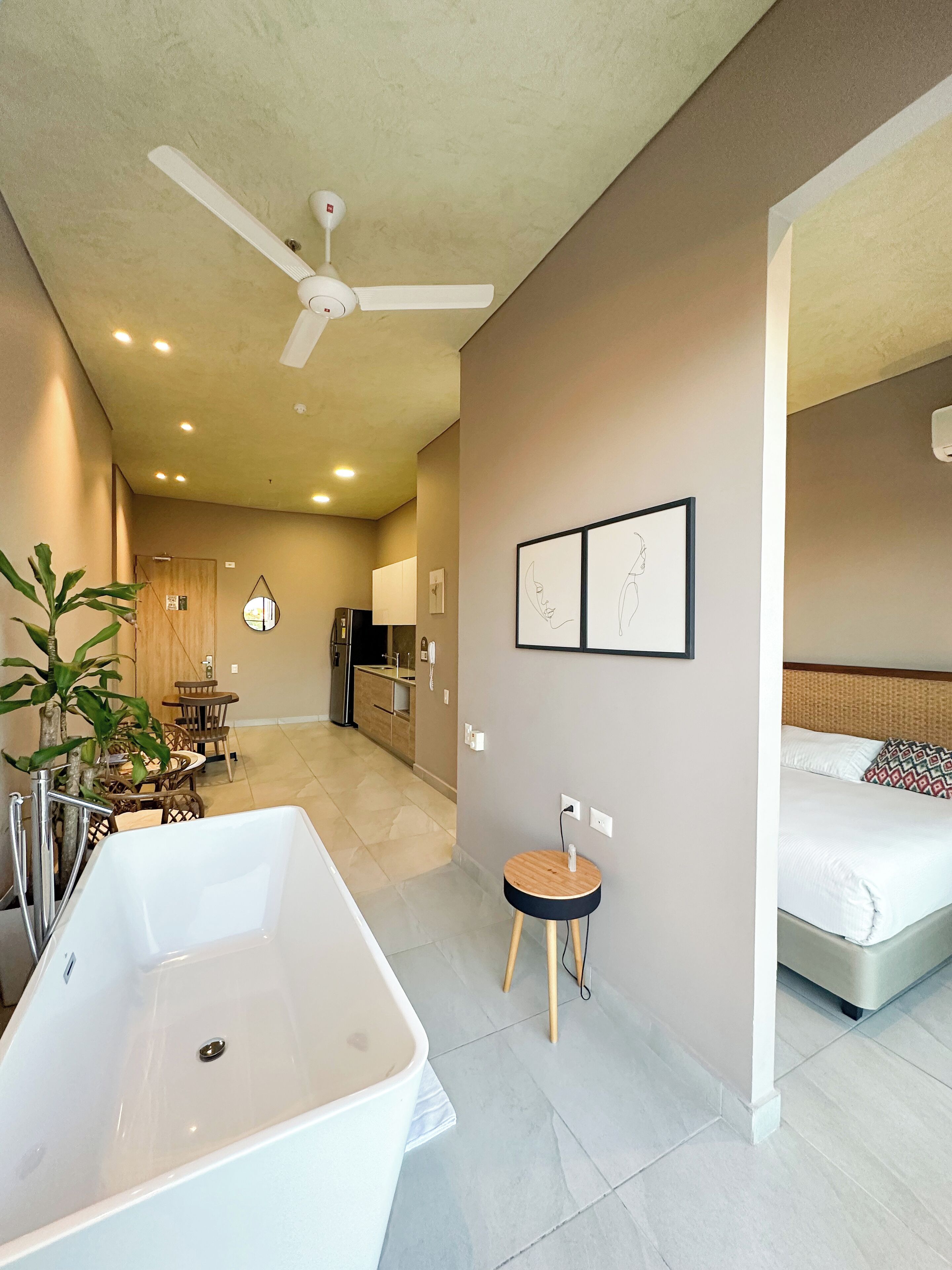Une salle de bain moderne avec une baignoire sur pieds, un ventilateur de plafond et un petit tabouret rond.