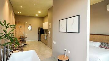 Une salle de bain moderne avec une baignoire sur pieds, un ventilateur de plafond et un petit tabouret rond.