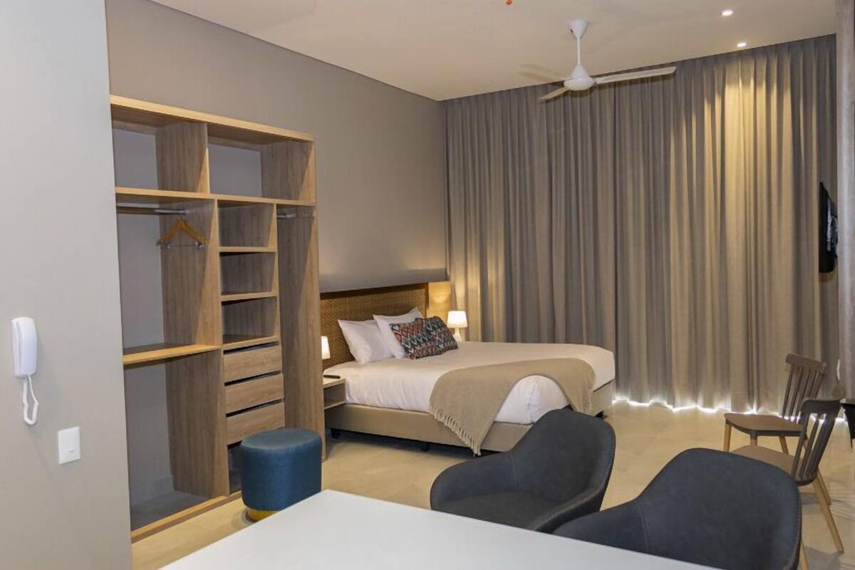 A hotel room with a bed, a wardrobe, a desk, and a chair.
