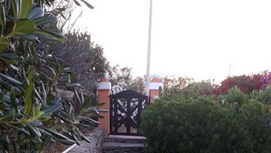 A stone pathway leading to a gate, surrounded by greenery and a pool area. - Villa Camilla private garden and pool. 30% DISCOUNT, PERIOD 24 MAY - 7 JUNE (Punta de Su Turrione Stintino ( SS))