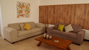 Twee banken met kussens, een houten salontafel en een decoratieve vaas.