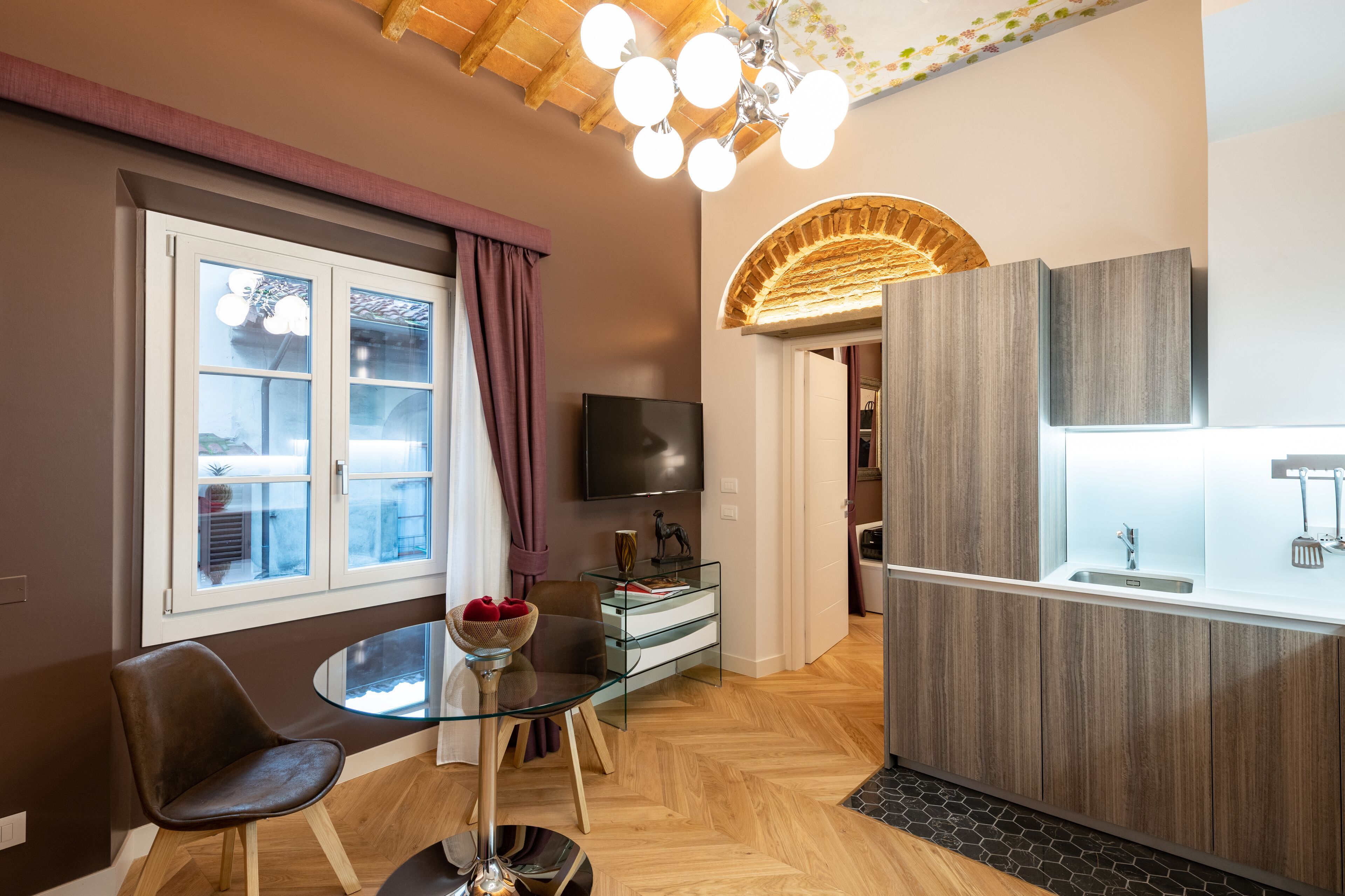 A modern living space with a dining area, a kitchen, and a TV mounted on the wall.