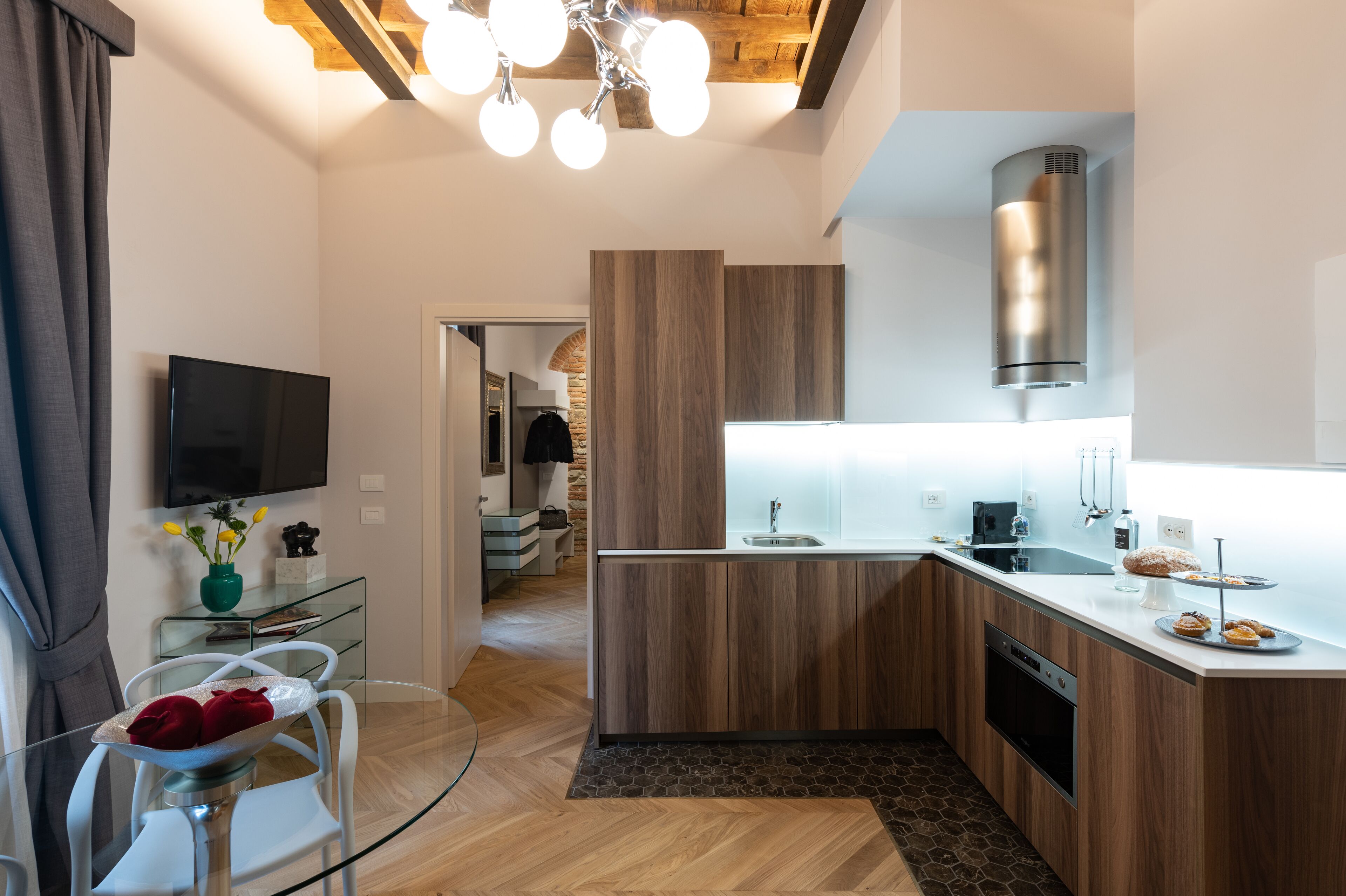 A modern kitchen with wooden cabinets, a built-in oven, and a stainless steel range hood.