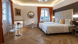 Habitación de hotel con una cama grande, una pequeña mesa con sillas, un espejo redondo y un candelabro.