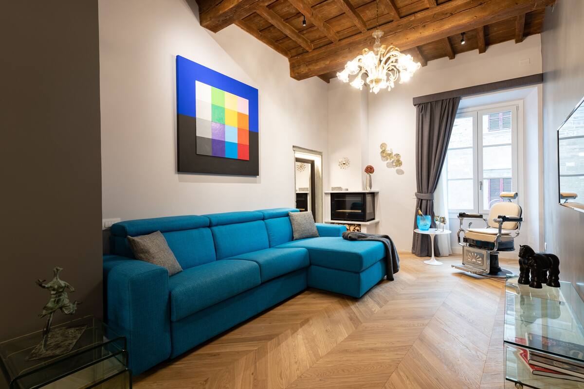 Una sala moderna con un sofá azul, una televisión y una araña.