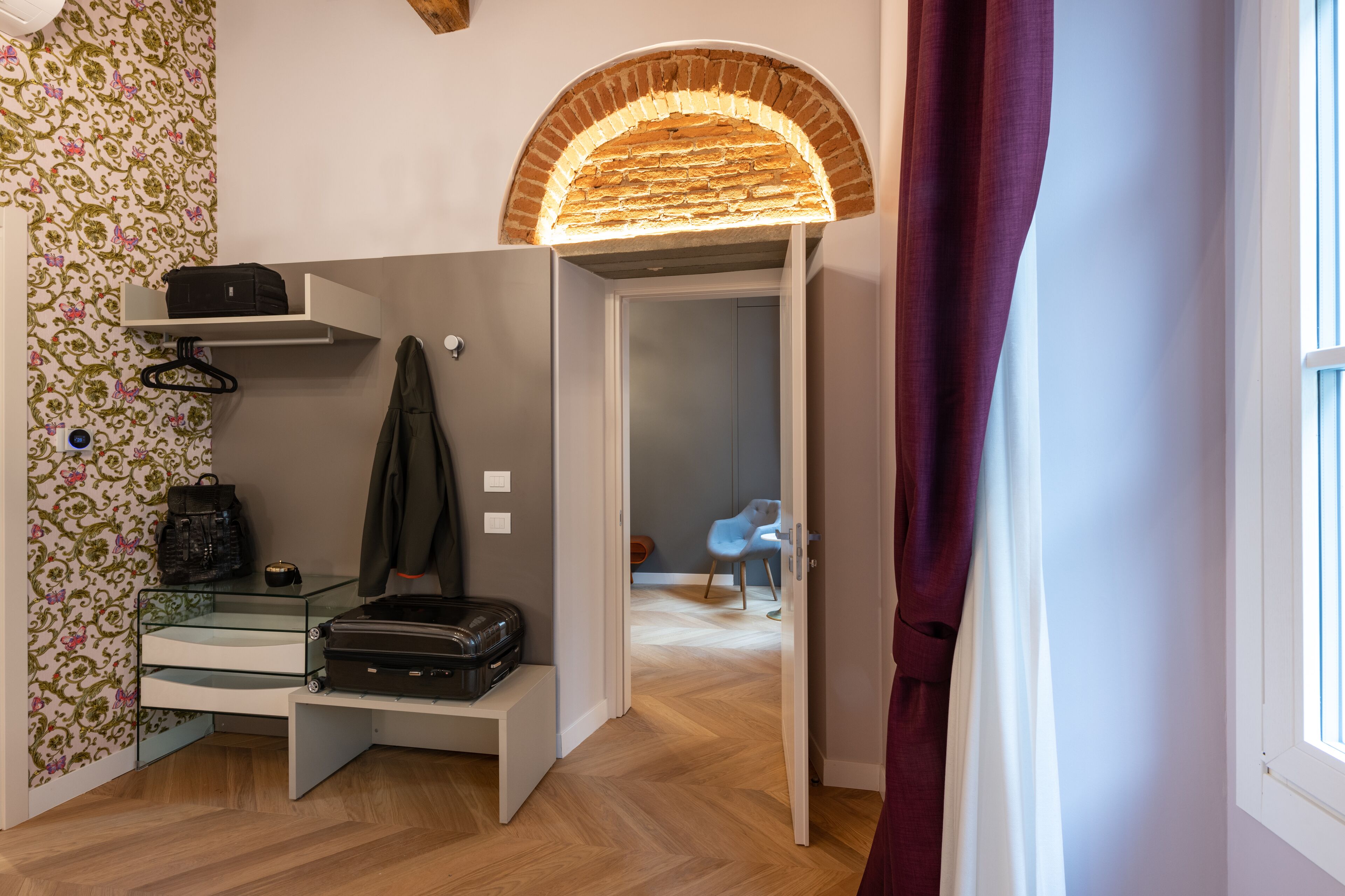 Une pièce comprenant un banc, une valise, un manteau et un porte-manteau mural.