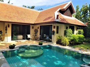 Ein Haus mit Swimmingpool, Sitzgelegenheiten im Freien und einem Garten.
