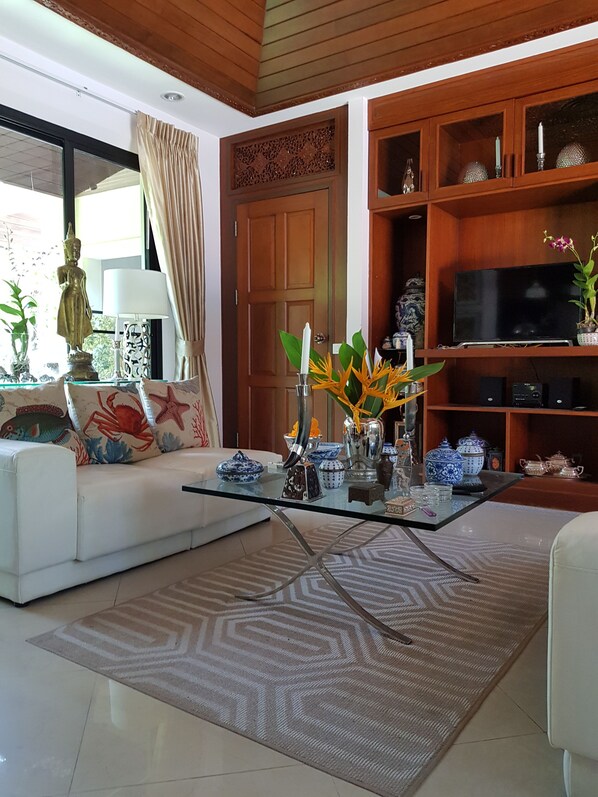 A living room with a white sofa, glass coffee table, and decorative items.