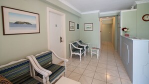 A hallway with a bench, two chairs, a small table, and a refrigerator. - Sunny Garden (Lefkada)