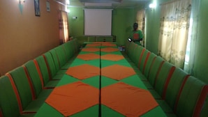 A conference room with green and orange seating, a projector screen, and curtains. - Winner's Resort (Machakos)
