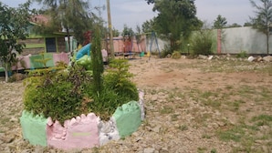A garden with a small tree, a swing set, and a dirt path. - Winner's Resort (Machakos)