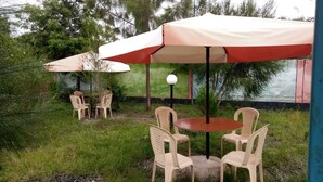 An outdoor seating area with a round table and four chairs, covered by a large umbrella. - Winner's Resort (Machakos)