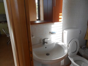 Een badkamer met een wit wastafelmeubel, toilet en kast.