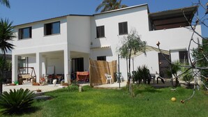 A two-story house with a covered patio, a swing, and a small garden area. - Villa Lucia 50 meters from the sea (Avola)