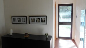 A room with a black cabinet, two framed pictures on the wall, and a door with blinds. - Villa Lucia 50 meters from the sea (Avola)