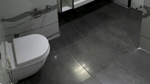 Ein modernes Badezimmer mit einem weißen Waschbecken, einer Toilette und einem Spiegel.