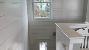 Un escalier étroit avec des rampes blanches et une petite fenêtre en haut.