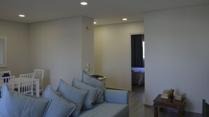 Uma sala de estar moderna com um sofá, cadeiras e uma pequena mesa com livros.