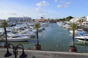 A marina with numerous boats docked along a canal, surrounded by buildings and palm trees.