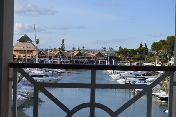 A marina with boats docked, a building with a pyramid-shaped roof, and palm trees in the background.