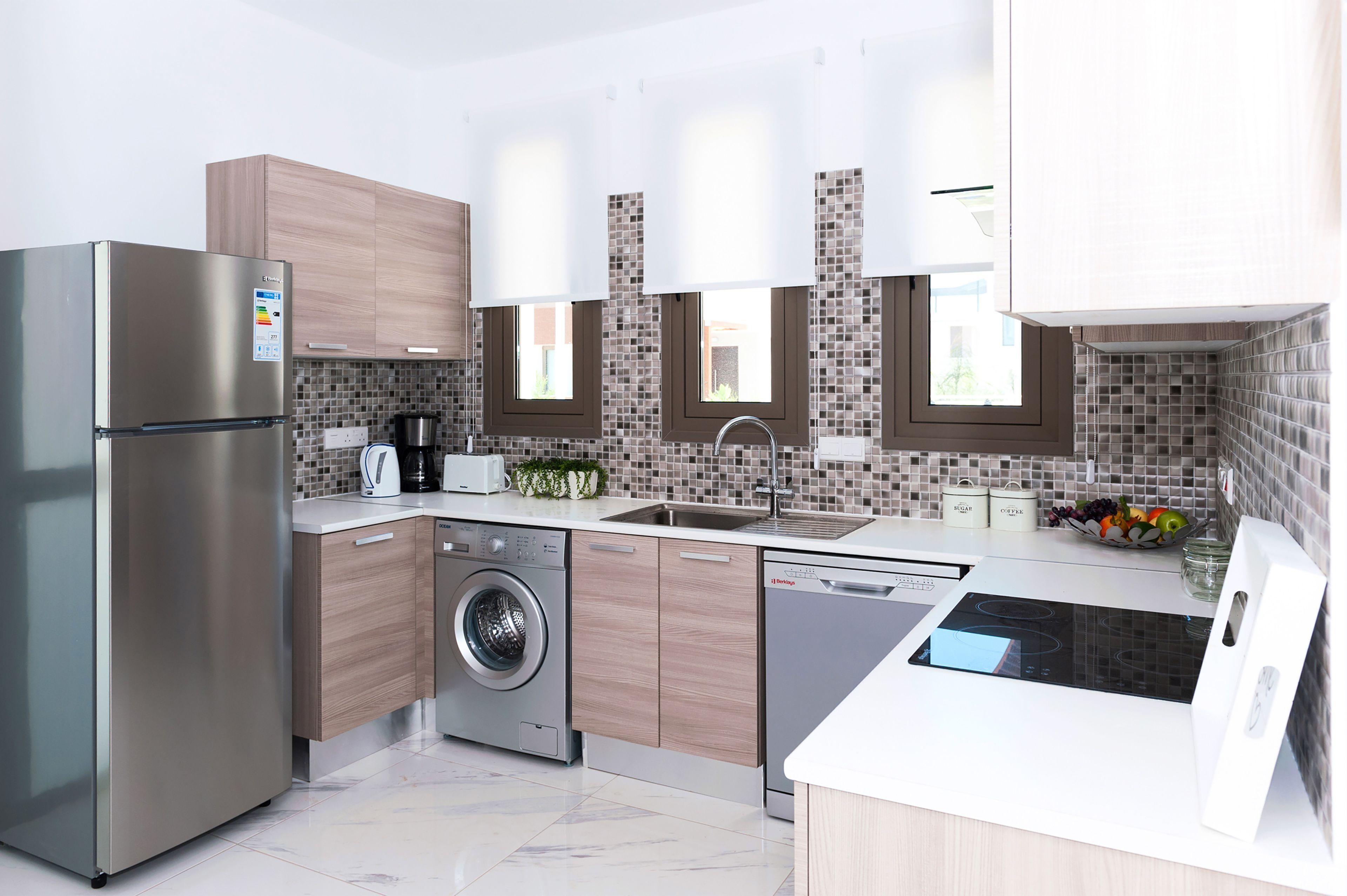 Una cocina moderna con electrodomésticos de acero inoxidable, armarios de madera, lavadora integrada y cocina de color negro.