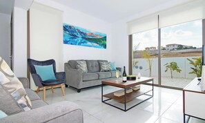 Una sala de estar moderna con un sofá gris, un sillón azul y una mesa de centro con una botella y un vaso.