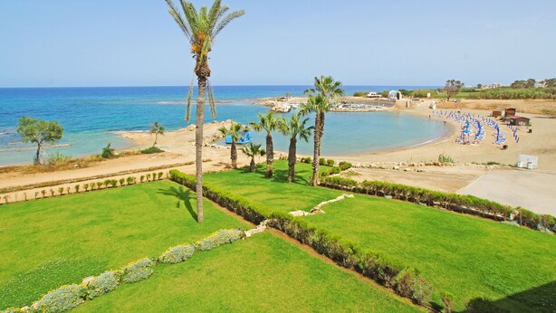 A coastal landscape with a beach, palm trees, and a clear sky. - SERENA - Brand New 4Bed Villa walking distance to Trinity Golden Sandy Beach (Paralimni)