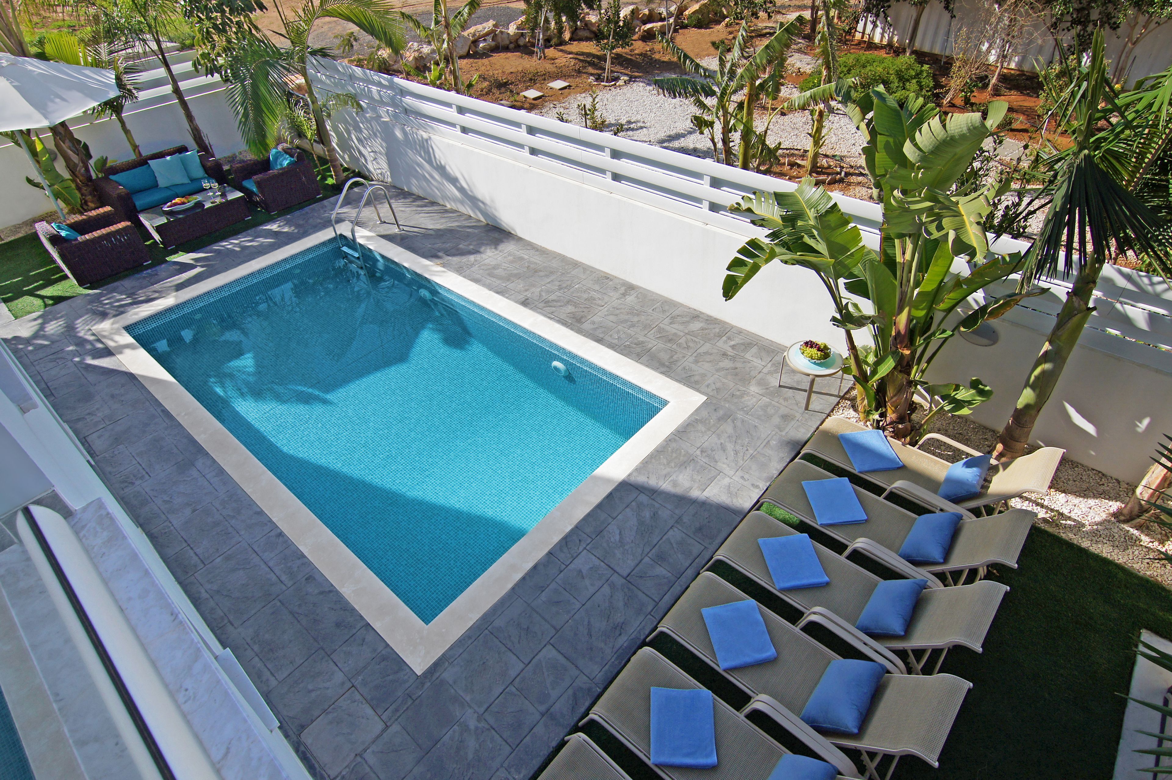 A swimming pool with lounge chairs and a seating area with a table and chairs.