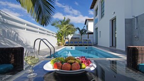 A poolside setting with a table, lounge chairs, and a fruit platter. - SERENA - Brand New 4Bed Villa walking distance to Trinity Golden Sandy Beach (Paralimni)