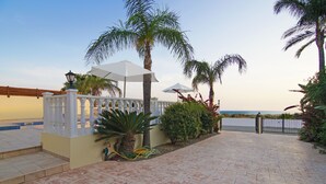A patio area with tiled flooring, white columns, and palm trees. - VILLA CLEOPATRA  - 4bed Villa with large pool in Ayia Napa Hills (Paralimni)