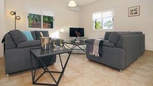 A modern living room with two grey sofas, a black coffee table, and a flat-screen TV. - VILLA CLEOPATRA  - 4bed Villa with large pool in Ayia Napa Hills (Paralimni)