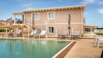 Relax by the pool surrounded by lounge chairs and umbrellas.