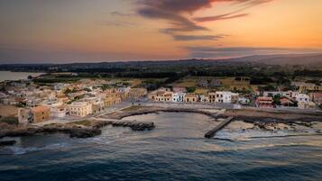 A coastal town with buildings along the waterfront, a clear sky, and a sunset.