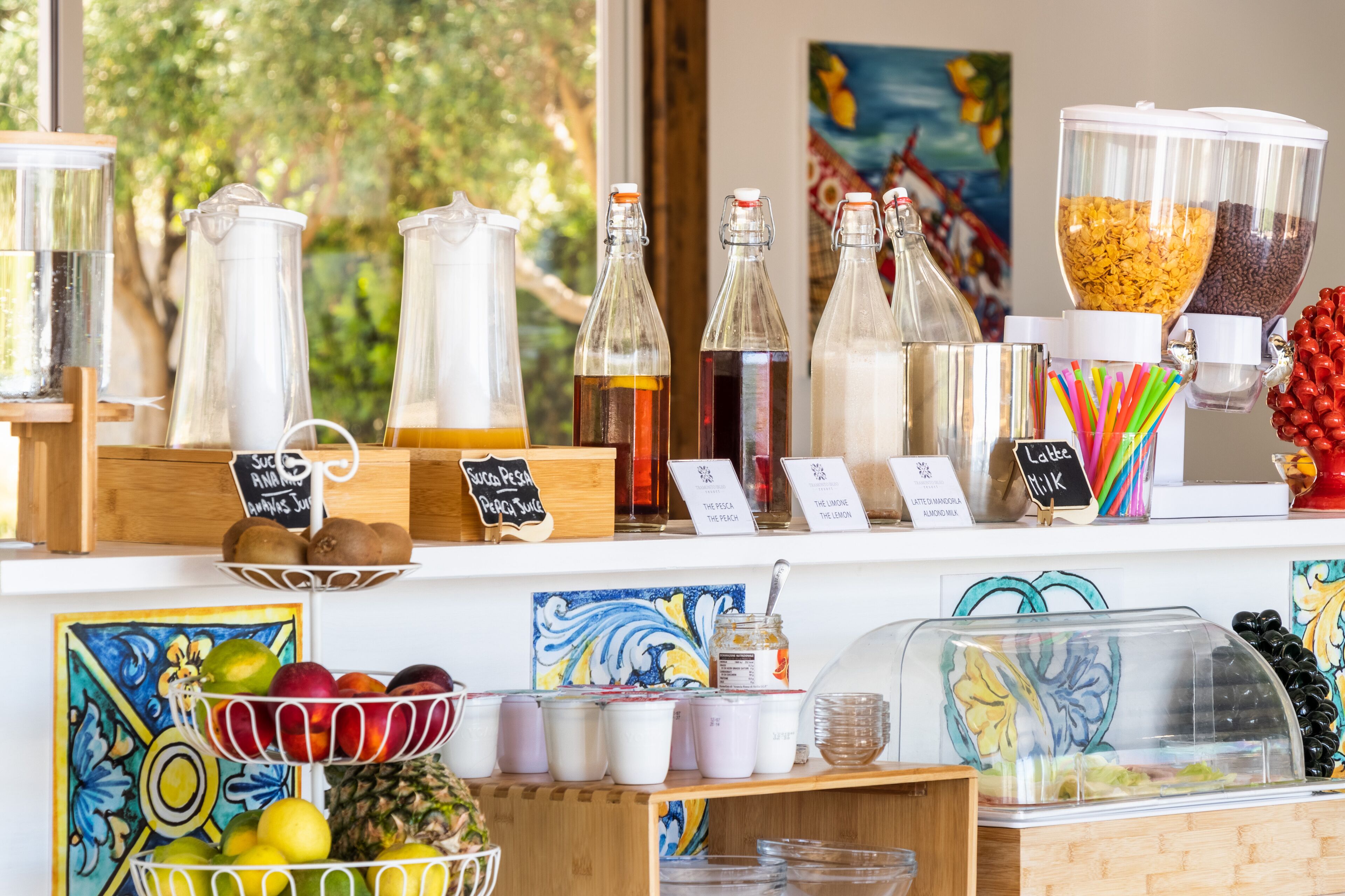 A café counter with various beverages and food items, including a fruit bowl, jars, and a coffee machine.