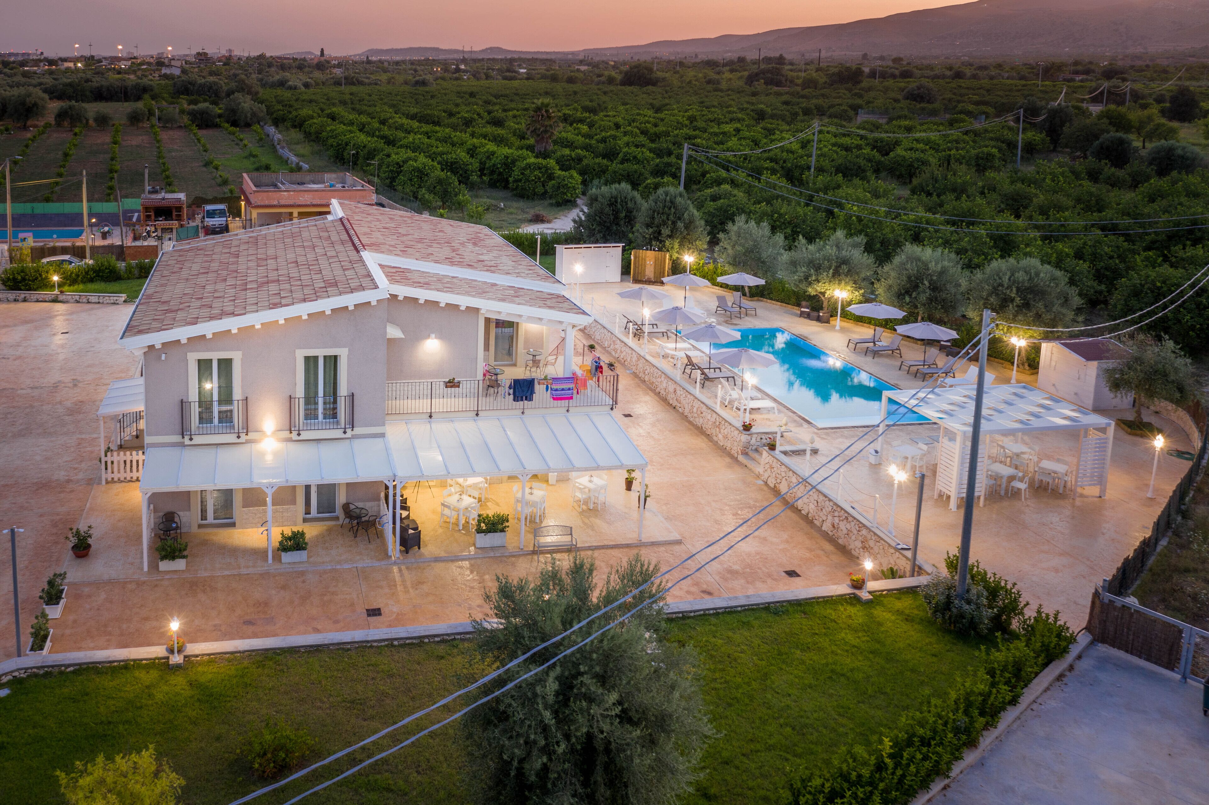 Una villa con piscina, mobiliario exterior y un patio cubierto.