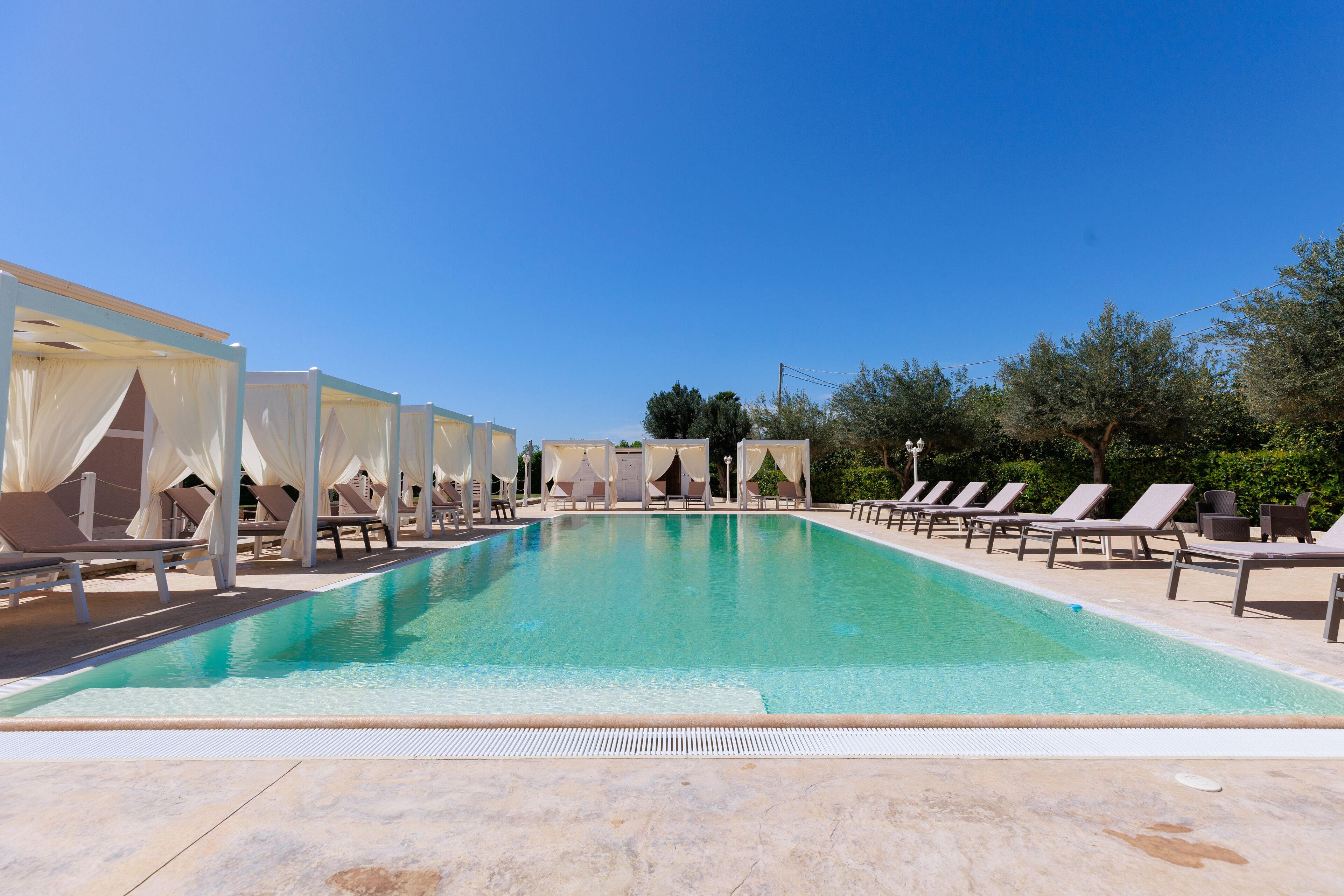 Une piscine dotée de chaises longues et d’espaces de repos abrités.