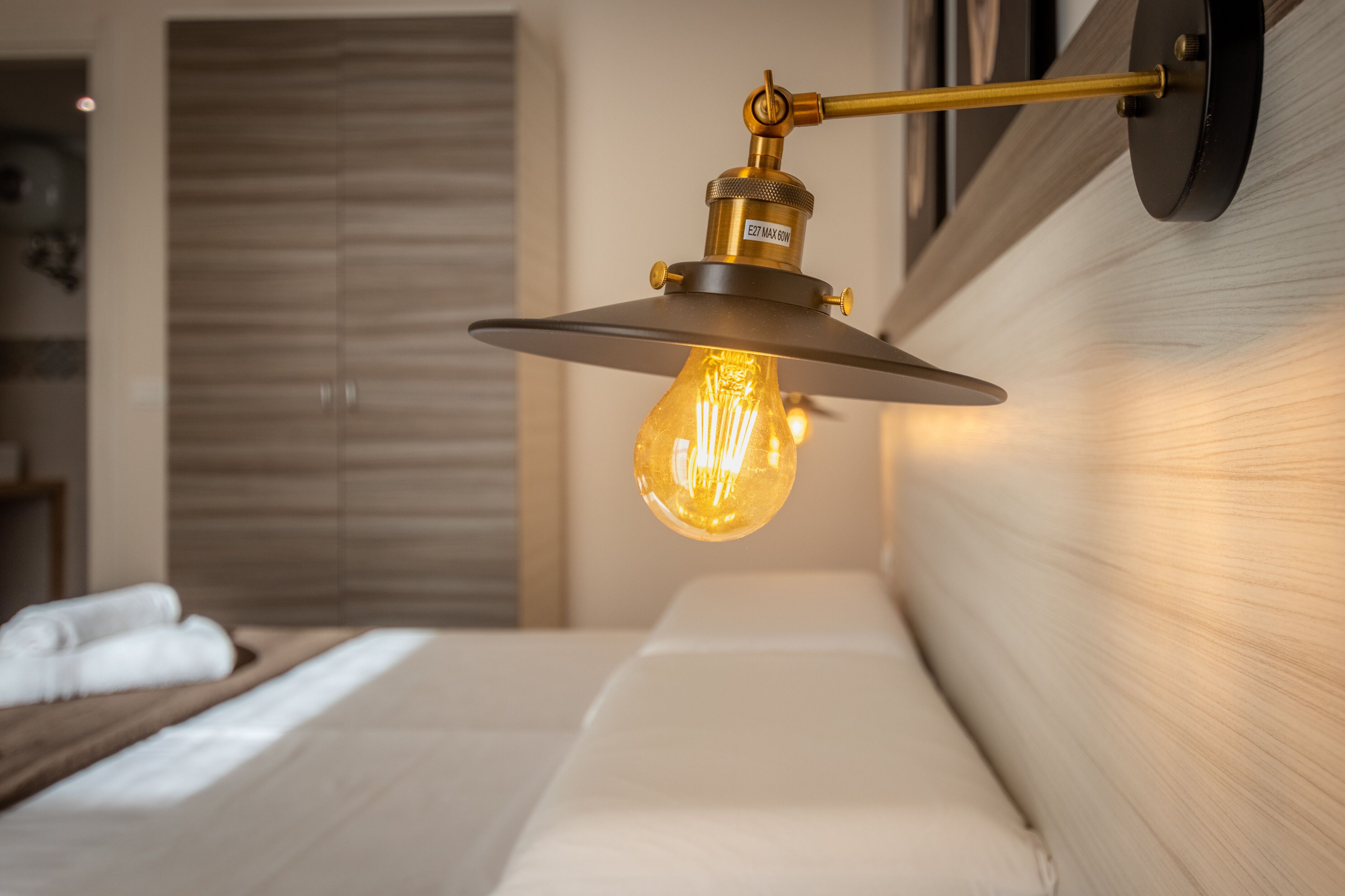 Een moderne slaapkamer met een bed, een wandlamp en een houten hoofdeinde.