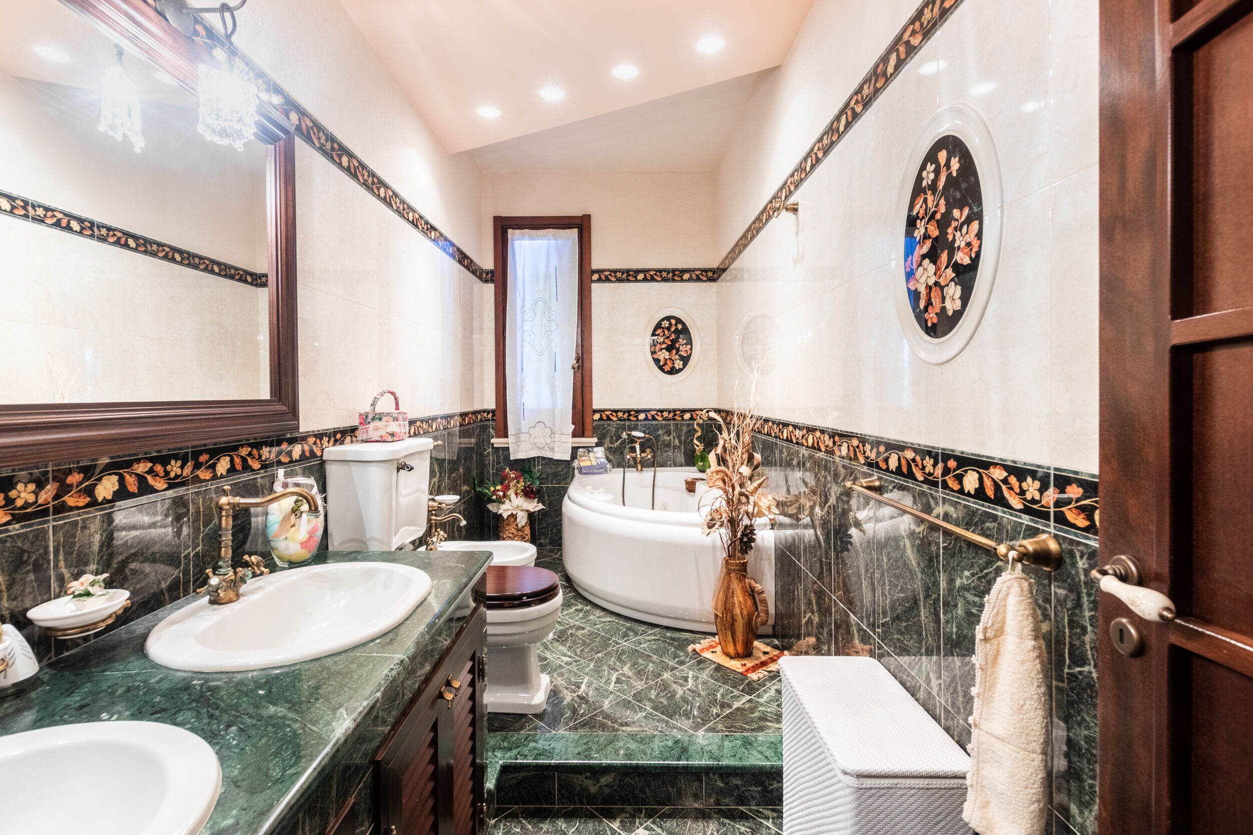 Une salle de bain luxueuse avec deux lavabos, des toilettes, une baignoire et un grand miroir.