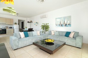 Una sala de estar moderna con un conjunto de sofás, una mesa de centro con fruta y una pintura de un velero en la pared.