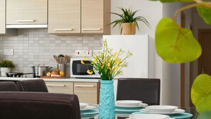 Une cuisine moderne avec une table à manger pour quatre personnes, un four à micro-ondes et une plante en pot posée sur le plan de travail.