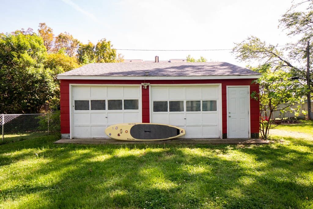 A red garage with two white doors and a single garage door.