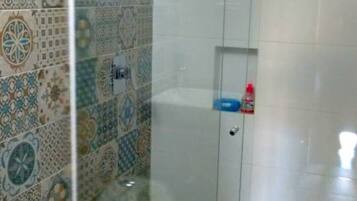 Un baño con cabina de ducha, inodoro y lavabo.