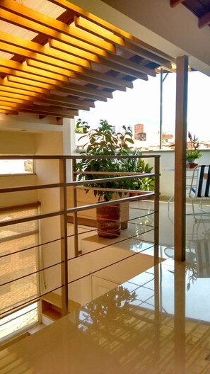 A modern interior with a glass railing, a wooden ceiling, and a view of a balcony with plants. - Private 501 with bathroom, TV closet and WI-FI (Bello)