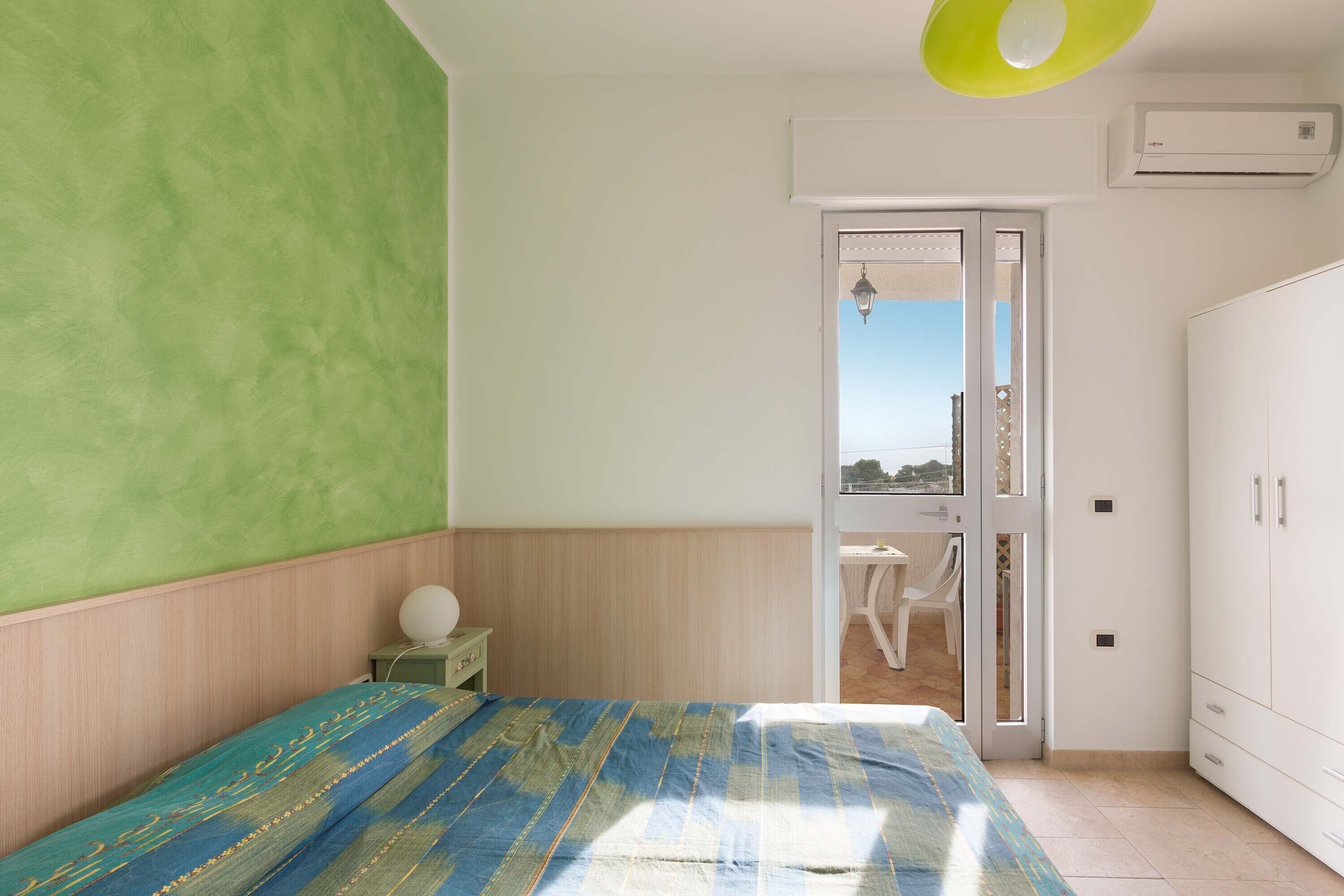 A bedroom with a bed, a desk, and a wardrobe.