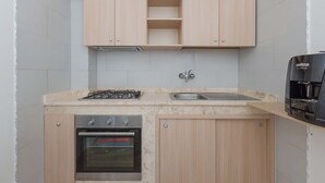 Cozinha compacta com fogão a gás, forno e máquina de café.